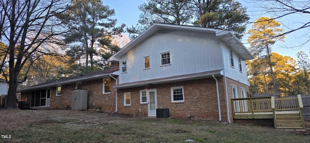 back of property featuring central AC, a deck, and a lawn