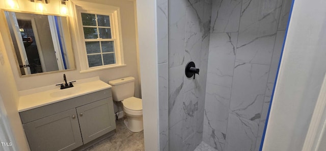 bathroom featuring vanity, tiled shower, and toilet