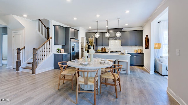 dining space featuring ornamental molding and light hardwood / wood-style flooring