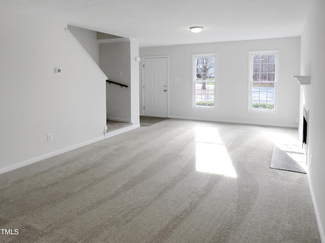130 Luxon Pl, Cary, NC 27513 - unfurnished living room featuring a fireplace with flush hearth, baseboards, stairway, and carpet