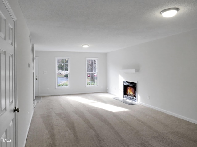 130 Luxon Pl, Cary, NC 27513 - unfurnished living room featuring carpet floors, baseboards, a lit fireplace, and a textured ceiling