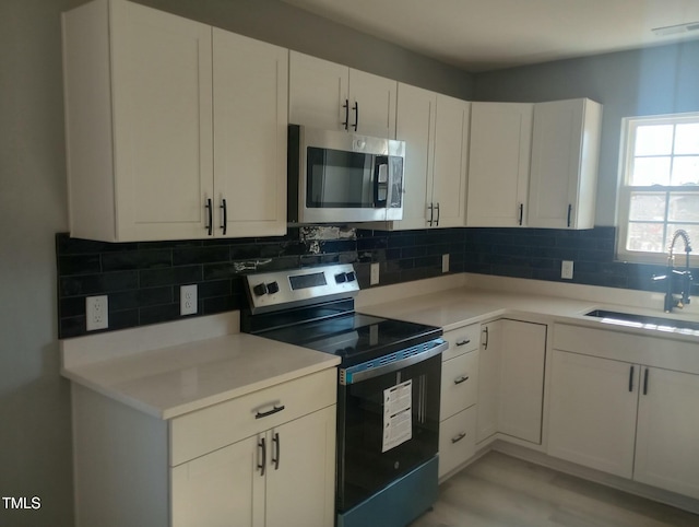 kitchen featuring white cabinetry, appliances with stainless steel finishes, sink, and backsplash