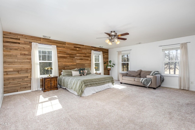 carpeted bedroom with ceiling fan and wood walls