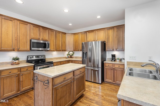 kitchen with a kitchen island, appliances with stainless steel finishes, sink, and light hardwood / wood-style floors