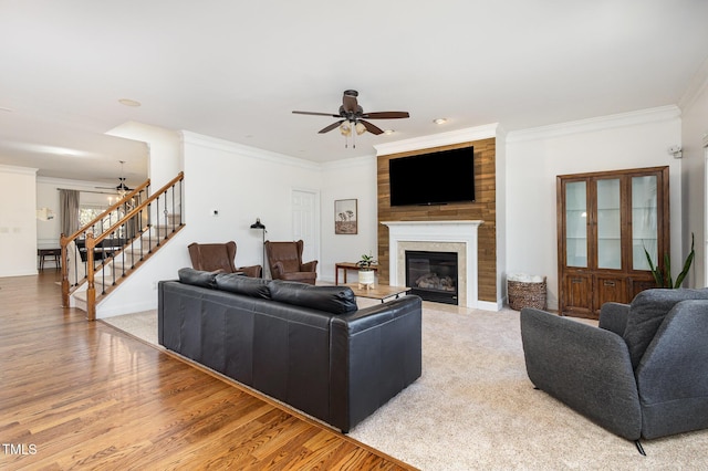 living room with ornamental molding, ceiling fan, and light wood-type flooring