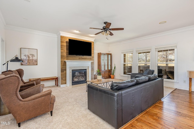 living room featuring crown molding, light hardwood / wood-style floors, a large fireplace, and ceiling fan