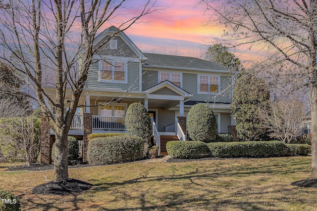 view of front of home with covered porch and a lawn