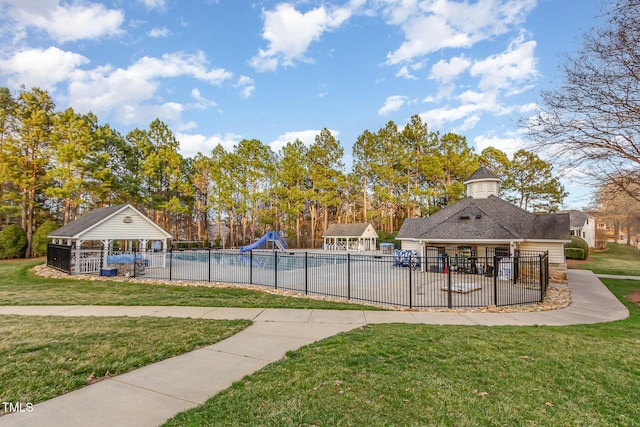 view of pool with a lawn, fence, a water slide, and a gazebo