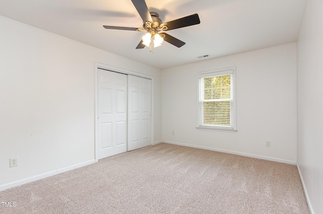 unfurnished bedroom with carpet floors, a closet, baseboards, and a ceiling fan