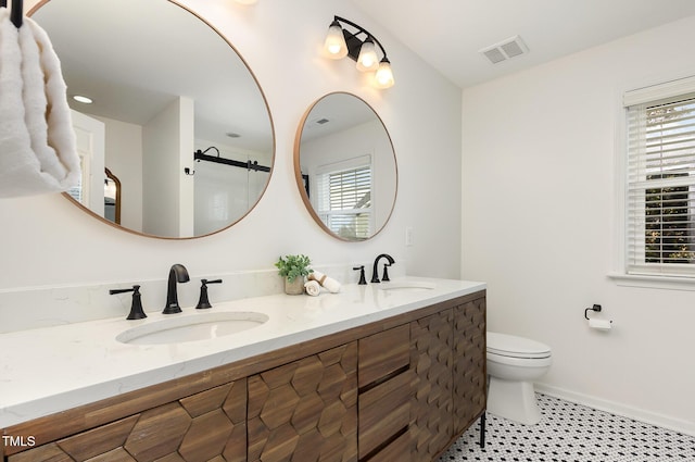 full bath with visible vents, a sink, toilet, and double vanity