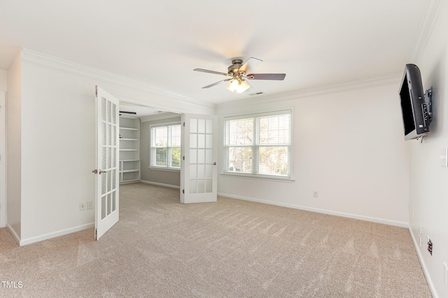 spare room featuring carpet floors, french doors, crown molding, a ceiling fan, and baseboards