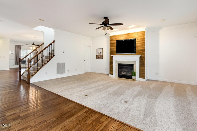 unfurnished living room featuring visible vents, stairway, ornamental molding, a fireplace with flush hearth, and wood finished floors