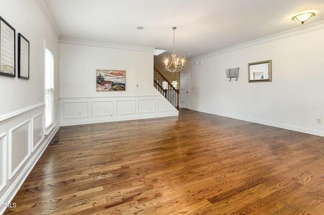 interior space featuring dark wood-style floors, ornamental molding, a decorative wall, and a notable chandelier