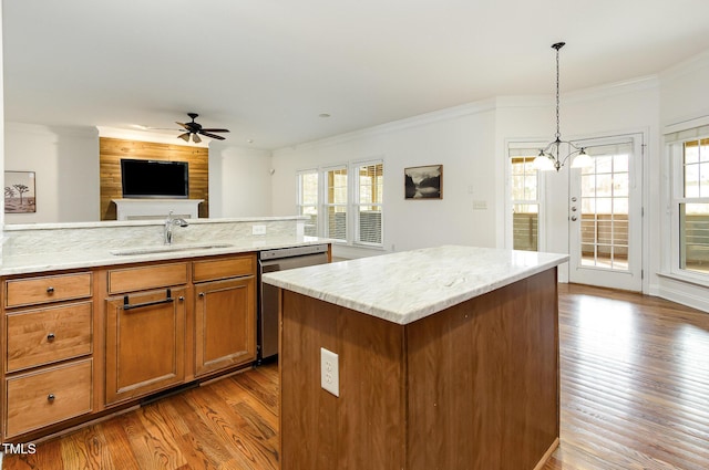 kitchen featuring dishwasher, brown cabinets, open floor plan, crown molding, and a sink