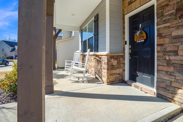 doorway to property featuring a porch and stone siding