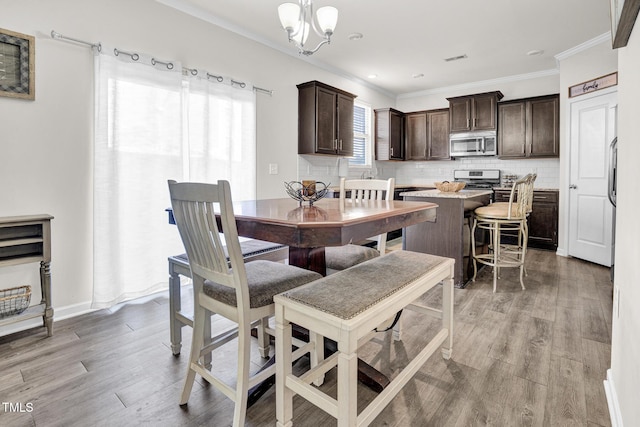 dining room with crown molding, a chandelier, and light wood-type flooring