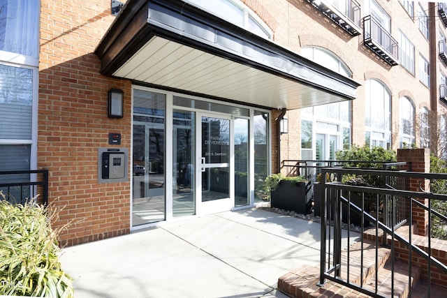 property entrance featuring a patio and brick siding