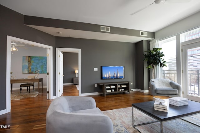 living area featuring a wealth of natural light, visible vents, and wood finished floors