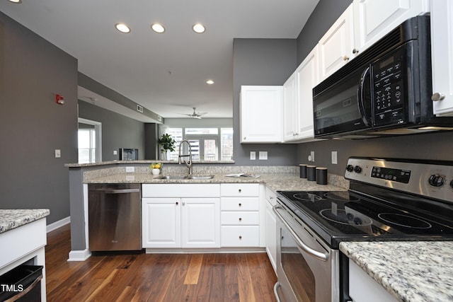 kitchen with white cabinets, light stone counters, appliances with stainless steel finishes, dark wood-type flooring, and a sink