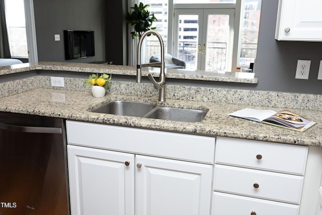 kitchen featuring french doors, white cabinetry, a sink, light stone countertops, and dishwasher