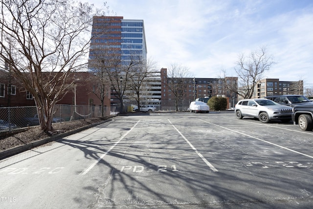 uncovered parking lot with fence and a city view