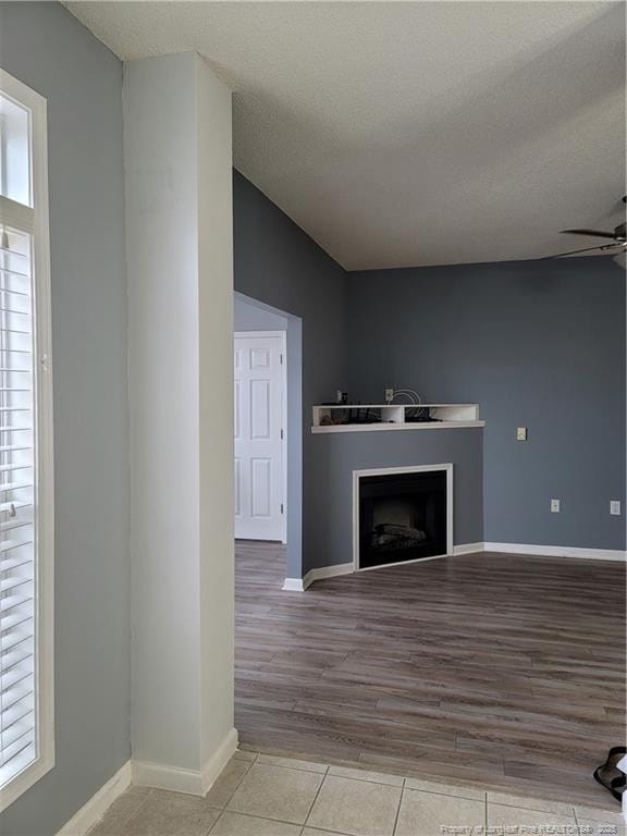 unfurnished living room with light tile patterned flooring, ceiling fan, plenty of natural light, and a textured ceiling