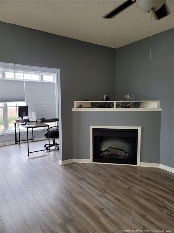 living room with hardwood / wood-style flooring, ceiling fan, and a textured ceiling