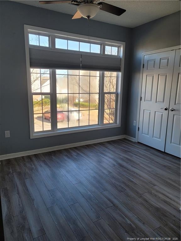 empty room with dark wood-type flooring, ceiling fan, and a textured ceiling