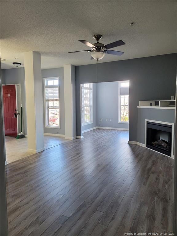 unfurnished living room featuring wood-type flooring, ceiling fan, and a textured ceiling