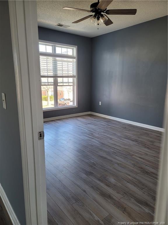 unfurnished room with ceiling fan, dark wood-type flooring, and a textured ceiling