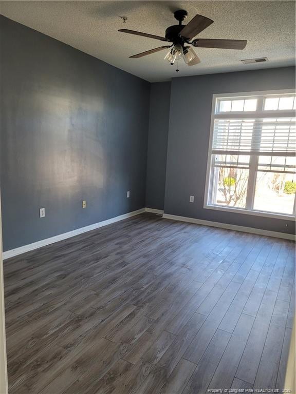 unfurnished room featuring dark hardwood / wood-style flooring, ceiling fan, and a textured ceiling