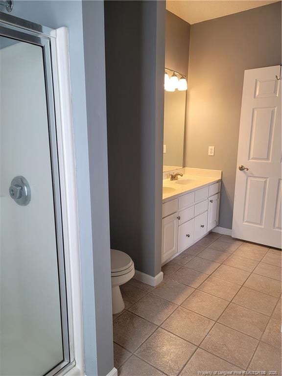 bathroom featuring tile patterned floors, vanity, toilet, and a shower with door