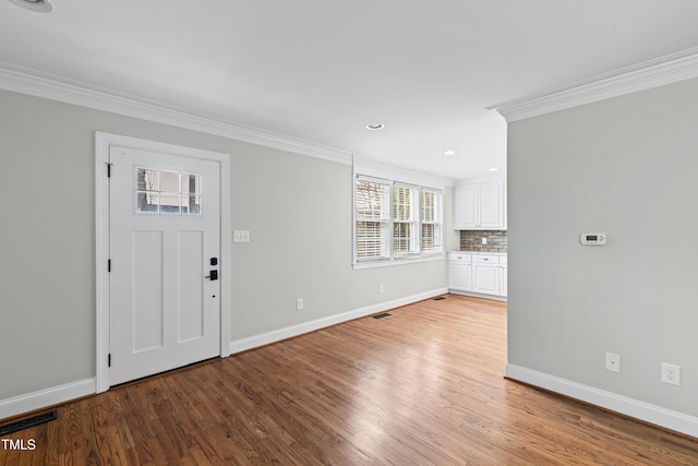 foyer entrance with ornamental molding and light wood-type flooring