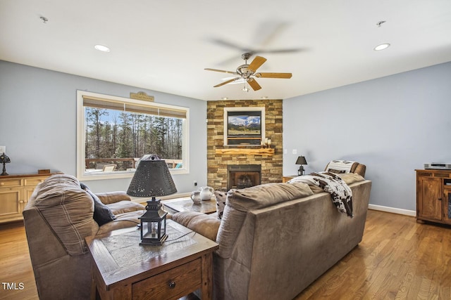 living room with ceiling fan, a fireplace, and light hardwood / wood-style flooring