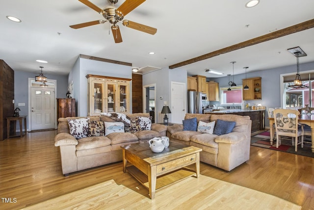 living room featuring beam ceiling, light hardwood / wood-style floors, and ceiling fan