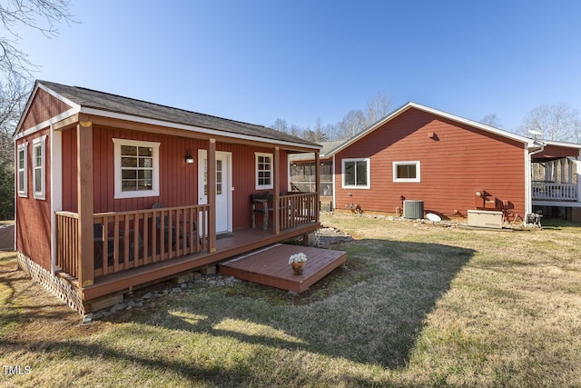 rear view of house with central AC unit and a lawn