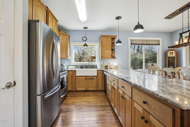 kitchen featuring sink, stone countertops, appliances with stainless steel finishes, kitchen peninsula, and pendant lighting