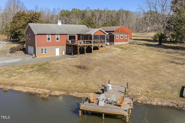 rear view of house featuring a deck with water view, a garage, and a lawn