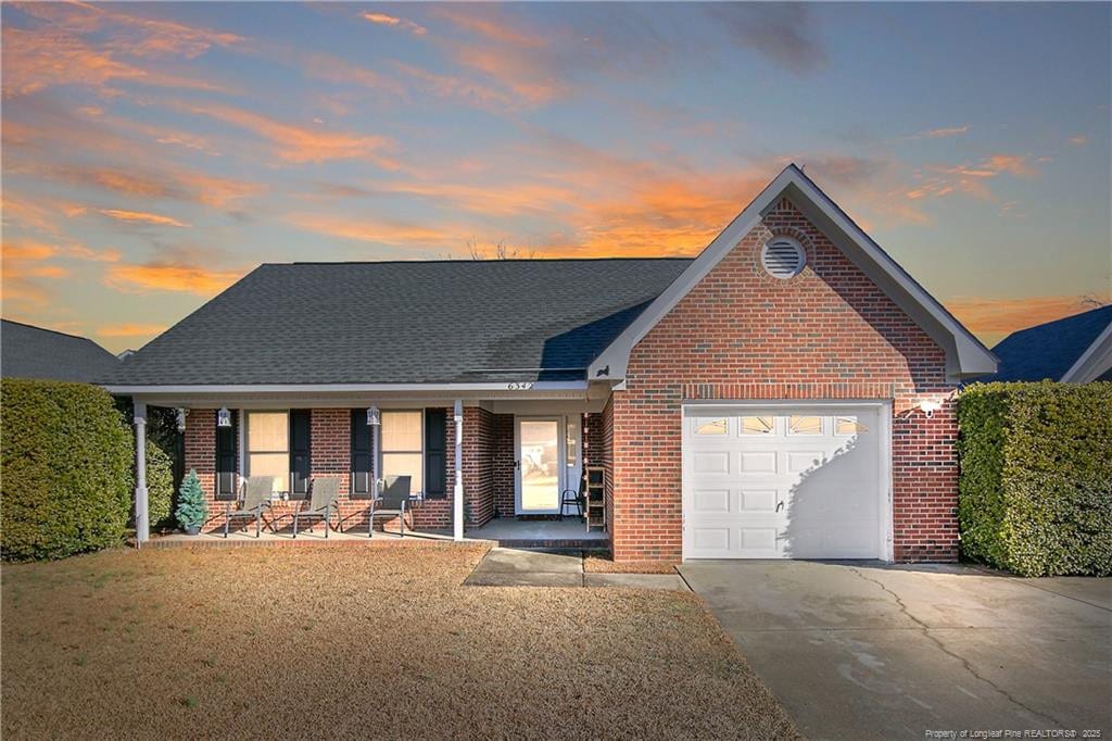 view of front of house featuring a garage, a lawn, and a porch