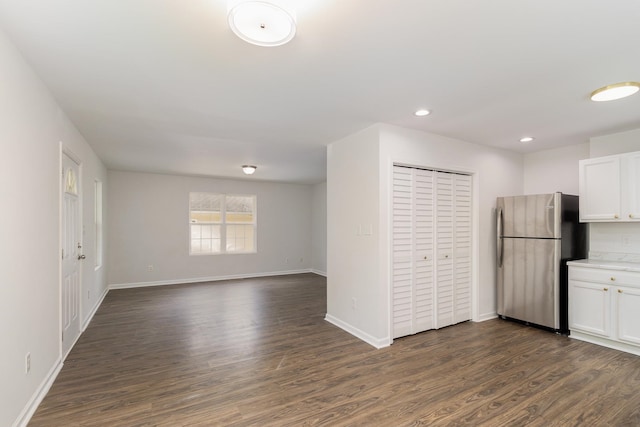 kitchen with stainless steel refrigerator, dark hardwood / wood-style flooring, and white cabinets