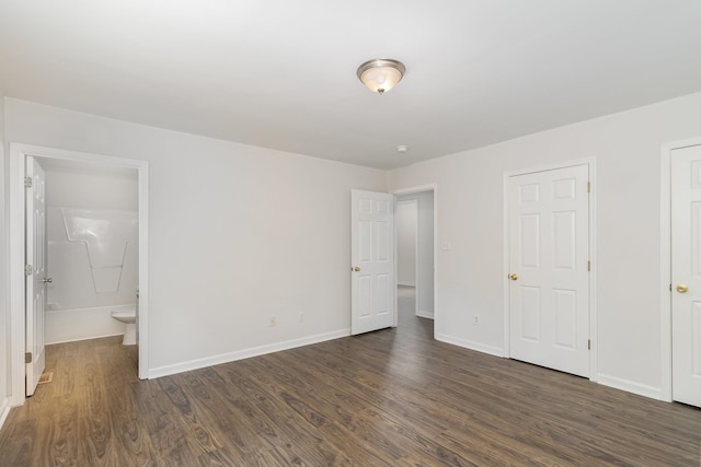 unfurnished bedroom with ensuite bathroom and dark hardwood / wood-style flooring