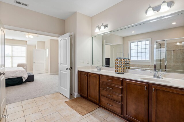 bathroom with double vanity, a stall shower, a sink, and visible vents