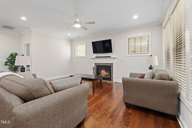 living room featuring dark wood finished floors, visible vents, ornamental molding, a fireplace with flush hearth, and baseboards