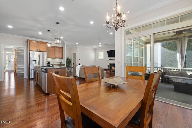 dining area with dark wood-style floors, a warm lit fireplace, and ornamental molding