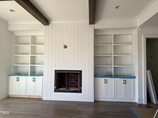 unfurnished living room with a fireplace, built in features, beam ceiling, and wood finished floors