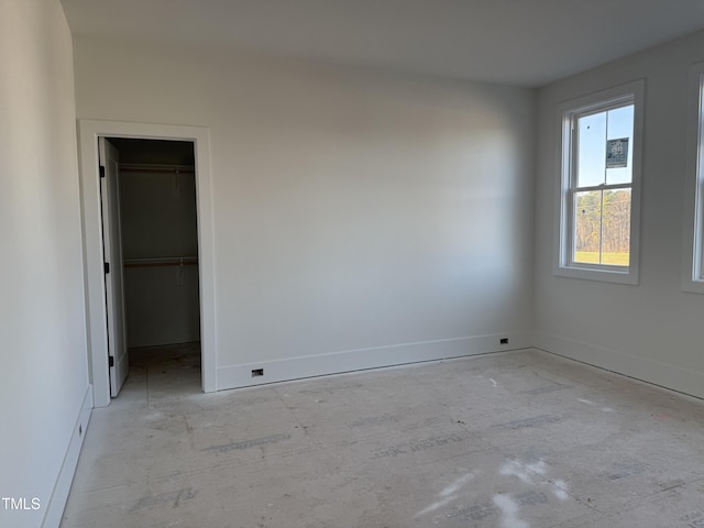 unfurnished bedroom featuring baseboards, a walk in closet, and a closet