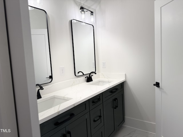 full bathroom featuring double vanity, marble finish floor, baseboards, and a sink