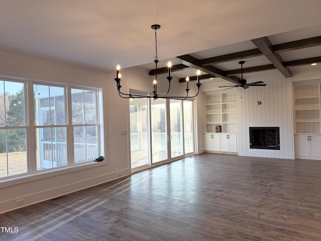 unfurnished living room featuring ceiling fan with notable chandelier, dark wood-style flooring, a fireplace, baseboards, and beamed ceiling