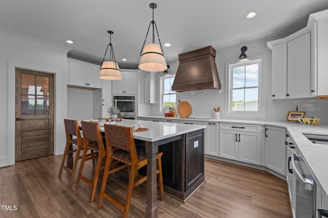 321 Bud Wall Rd, Youngsville, NC 27596 - kitchen with custom exhaust hood, a kitchen island, wood finished floors, white cabinets, and recessed lighting