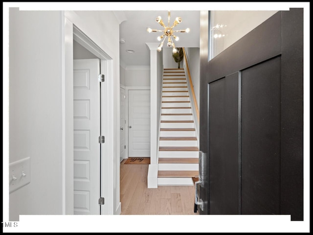 stairway featuring crown molding, wood-type flooring, and a chandelier